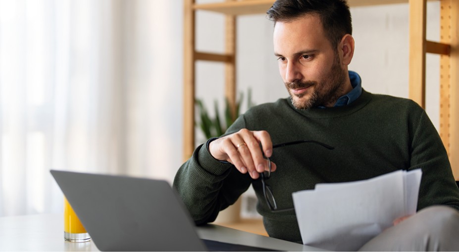 Man reviewing financial documents on a laptop while researching money market accounts