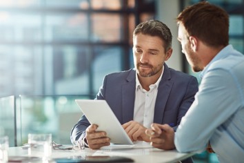 Bank advisor discussing account support options with client using tablet in office.